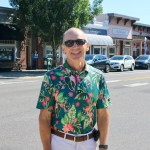 Outgoing Troutdale city manager Ray Young stands in a colorful shirt and sunglasses on a sunny day next to the Historic Columbia River Highway through Downtown.